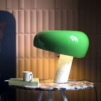 Green glossy lamp with a smooth, rounded shade on a textured marble base, surrounded by a subtle, warm background.