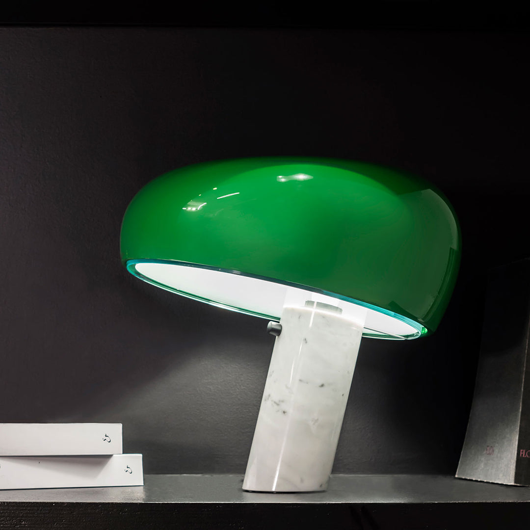 Green dome lamp with a smooth finish and a white marble base, set against a dark background.