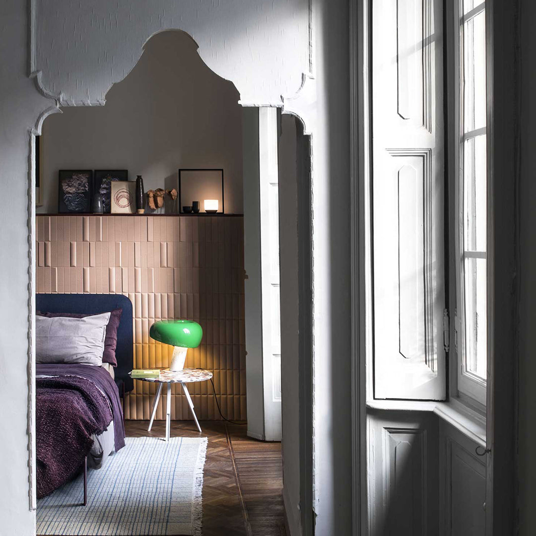Modern bedroom with deep purple bedding, soft gray textiles, and a vibrant green lamp against warm beige walls.
