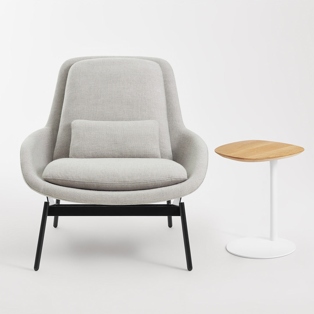 Gray upholstered chair with a minimalist design, featuring a light gray cushion and contrasting black legs next to a wooden side table.