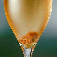 Golden champagne with a shimmering bubble and a hint of caramel color, elegantly contained in a sleek glass.