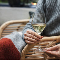 Cozy grey sweater with a red and white pattern, paired with a clear wine glass and a woven chair backdrop.
