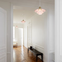 Pink pendant lights with gold accents in a minimalist white hallway, featuring elegant wooden flooring.