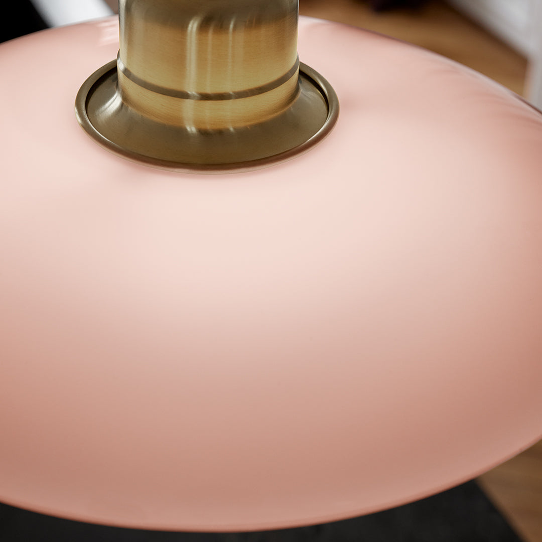 "Round pink glass pendant lamp with a sleek gold fixture and smooth finish."