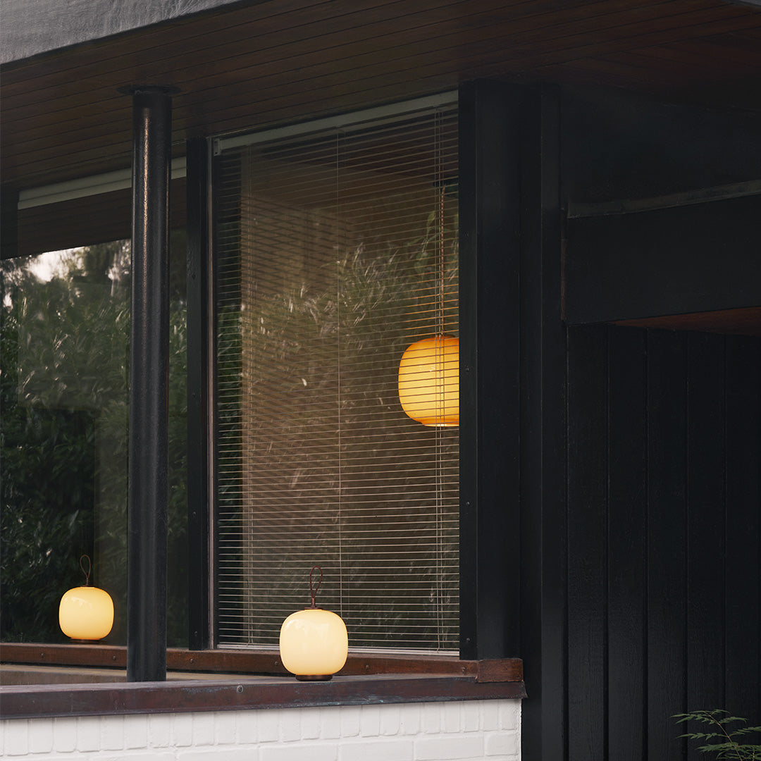 "Modern outdoor lanterns in soft amber and white hues, showcasing a minimalist design against a dark wood backdrop."