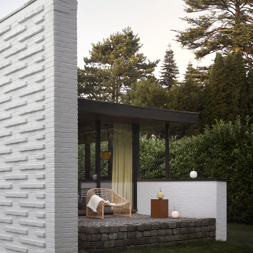 Modern white brick wall with textured pattern, natural stone elements, and vibrant greenery in a stylish outdoor setting.