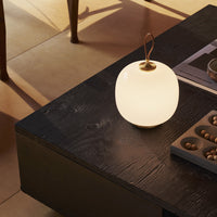 White round lamp with a smooth finish on a dark wooden table, featuring a subtle texture and warm lighting.