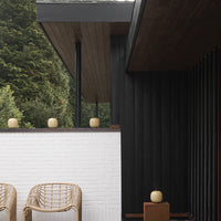 Black and white exterior with natural wooden accents, featuring wicker chairs and soft, round decorative elements.