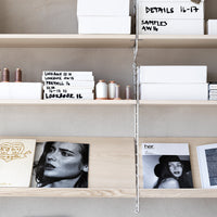 Minimalist shelves showcasing white boxes, light wood, and black and white magazine covers, creating a sleek, modern aesthetic.