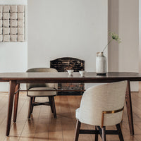 "Modern wooden dining table with neutral beige chairs and a minimalist vase, set against a light wall and wooden floor."