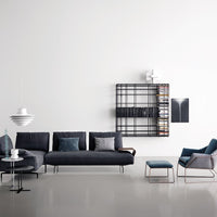 Modern living room featuring a dark gray sofa, teal accents, and a black geometric shelf against a white wall.