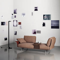 Brown and beige patterned sofa with sleek chrome legs, against a minimalist white wall and varied black-and-white art.