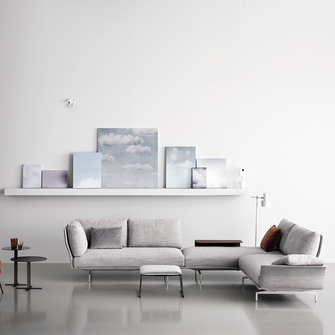 Modern light gray sectional sofa with subtle texture, accented by soft azure and white artwork on a minimalist shelf.