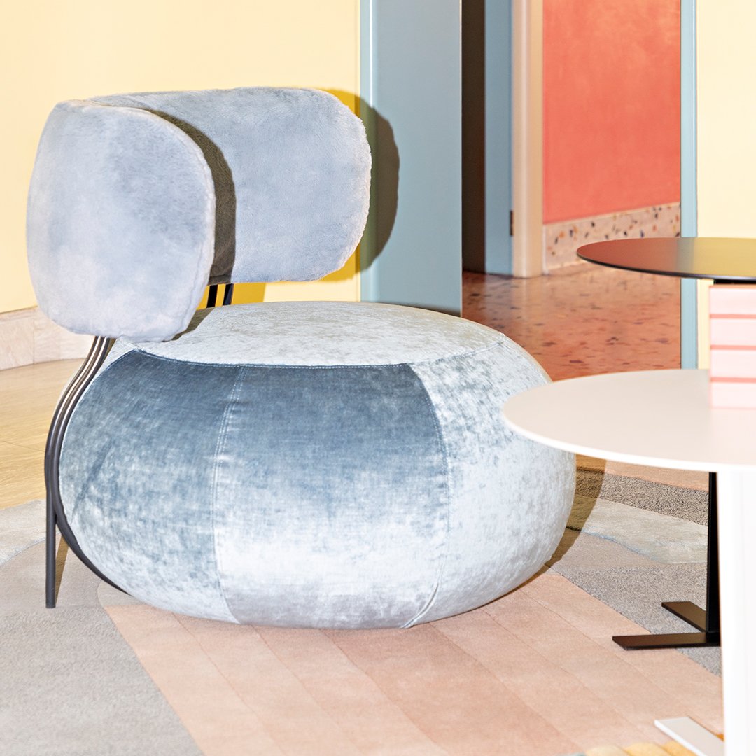 Modern light blue velvet armchair with soft curves and a patchwork design. Perfect for contemporary interiors.
