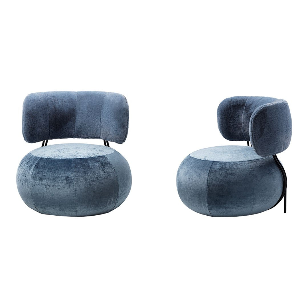 Luxurious blue velvet armchair with smooth, rounded shapes and a modern design, perfect for contemporary interiors.