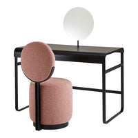 Pink upholstered chair and stool with a black metal desk and round mirror, featuring minimalist modern design.