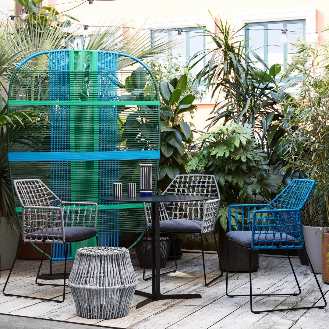"Stylish garden seating set featuring blue and gray patterns against lush greenery and a vibrant teal backdrop."