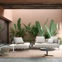"Modern outdoor seating in neutral tones with green plant accents and a textured beige rug."