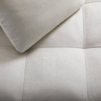 Soft beige fabric with a square quilted pattern and a smooth, light-colored pillow.