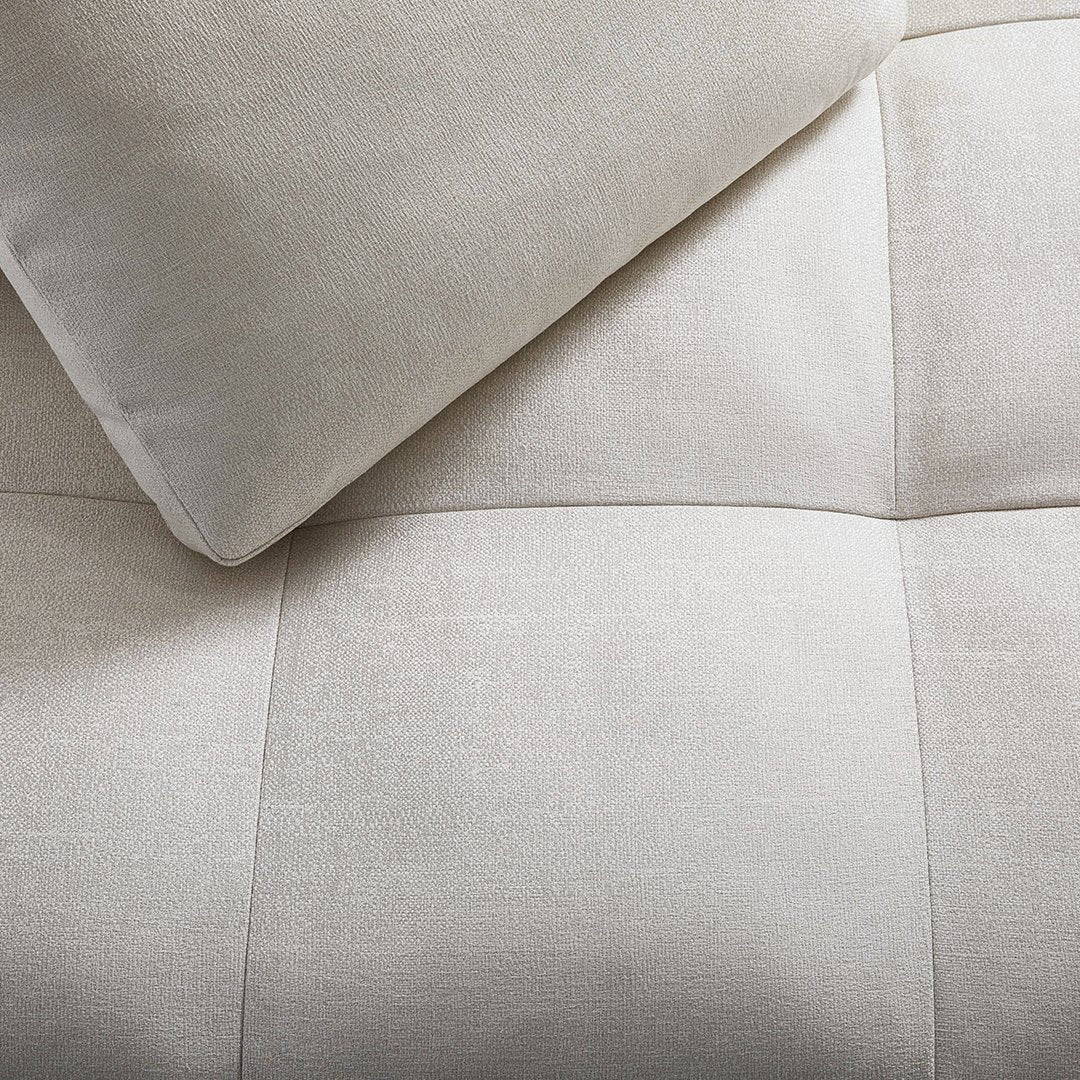 Light beige textured fabric with a grid pattern, featuring a matching soft cushion.