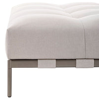 Light gray tufted ottoman with smooth fabric texture and a minimalist metal frame. Elegant and modern design.