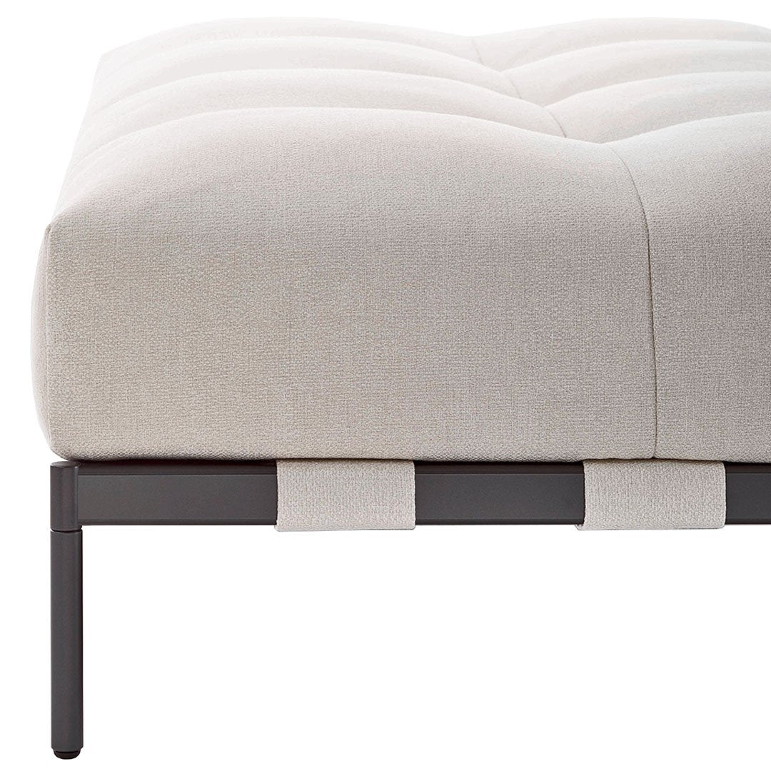 Light beige tufted cushion on a sleek black metal frame with contrasting fabric accents.