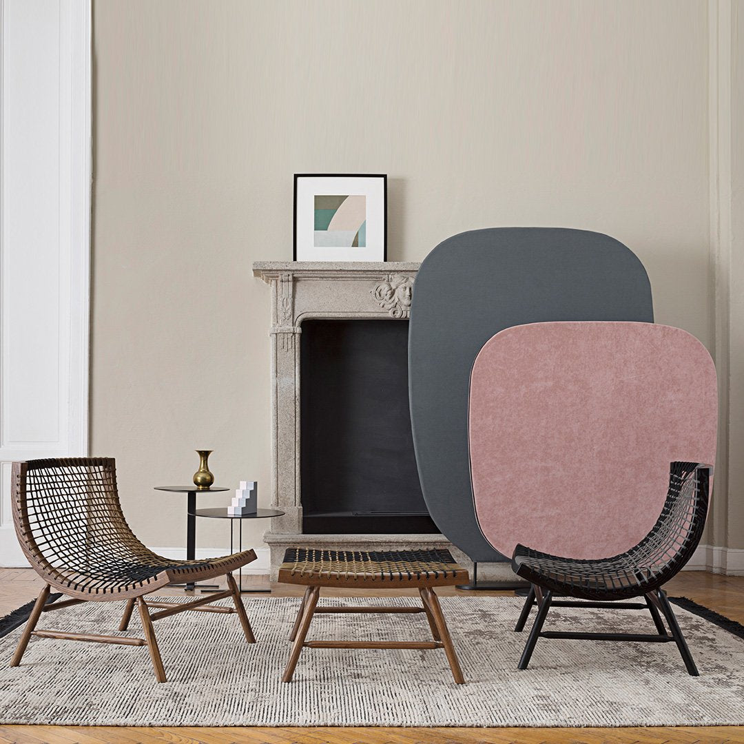 "Modern living room with soft pink and gray geometric wall art, natural wood furniture, and a neutral area rug."