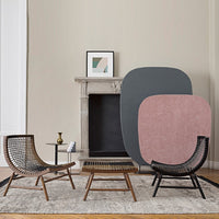 "Modern living room with soft pink and gray geometric wall art, natural wood furniture, and a neutral area rug."