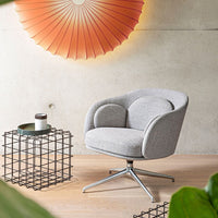 Gray upholstered chair with a textured pattern, set against a warm orange sunburst wall decoration.