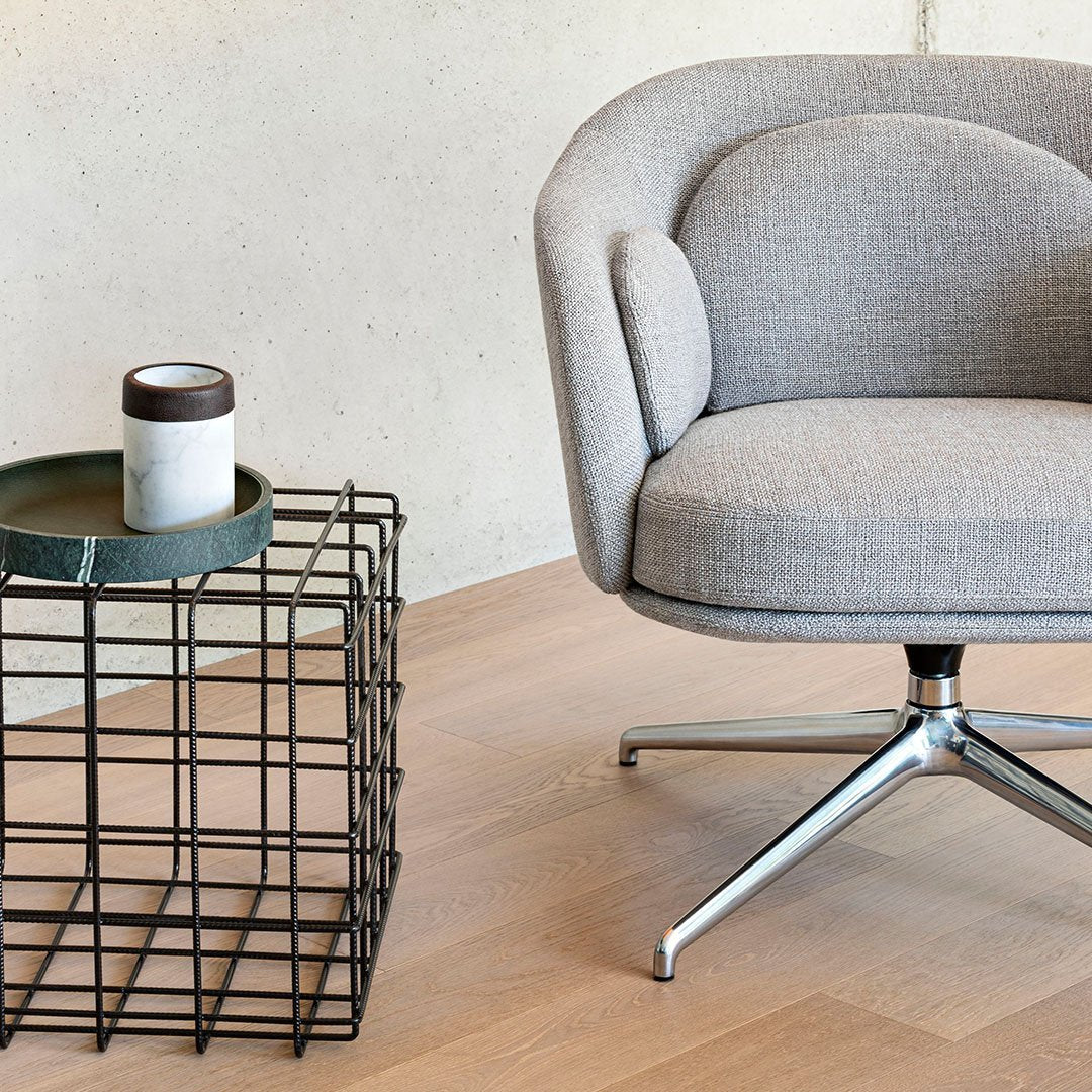 Gray upholstered chair with subtle textured pattern, alongside a modern black metal table with a matte white mug.