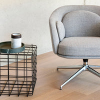 Gray upholstered chair with subtle textured pattern, alongside a modern black metal table with a matte white mug.