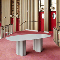 Elegant gray oval table with scalloped bases, set against vibrant red walls and a soft pink carpet.