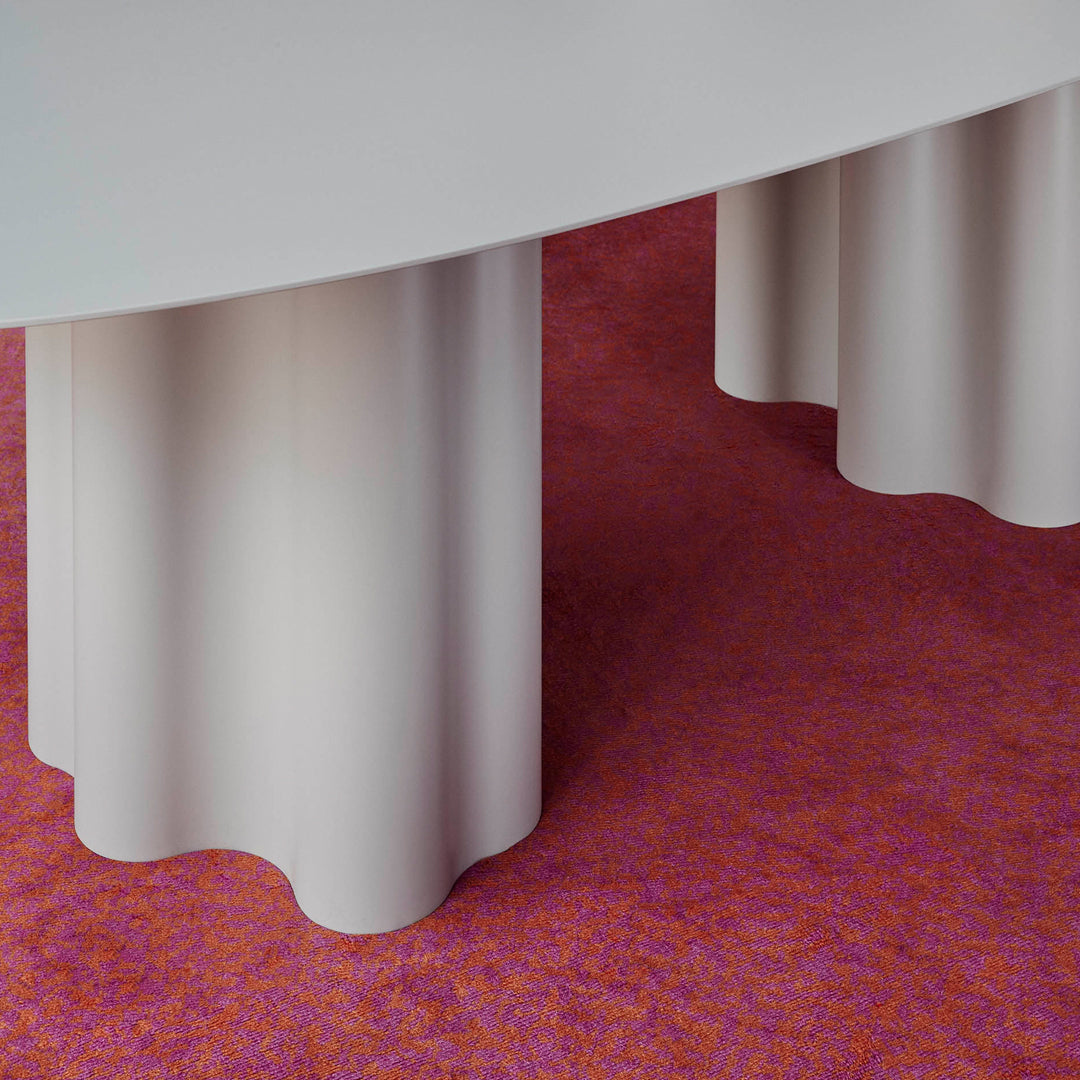 Curved gray table legs on a vibrant pink carpet, featuring subtle textures and patterns.