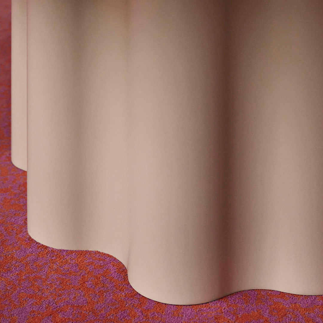 Beige fabric draping over a vibrant red and floral patterned carpet, showcasing soft textures and color contrast.
