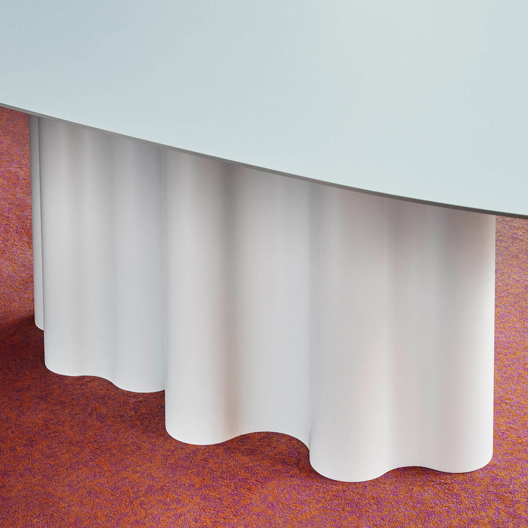 White scalloped table skirt against a vibrant orange textured surface. Elegant design for modern decor.