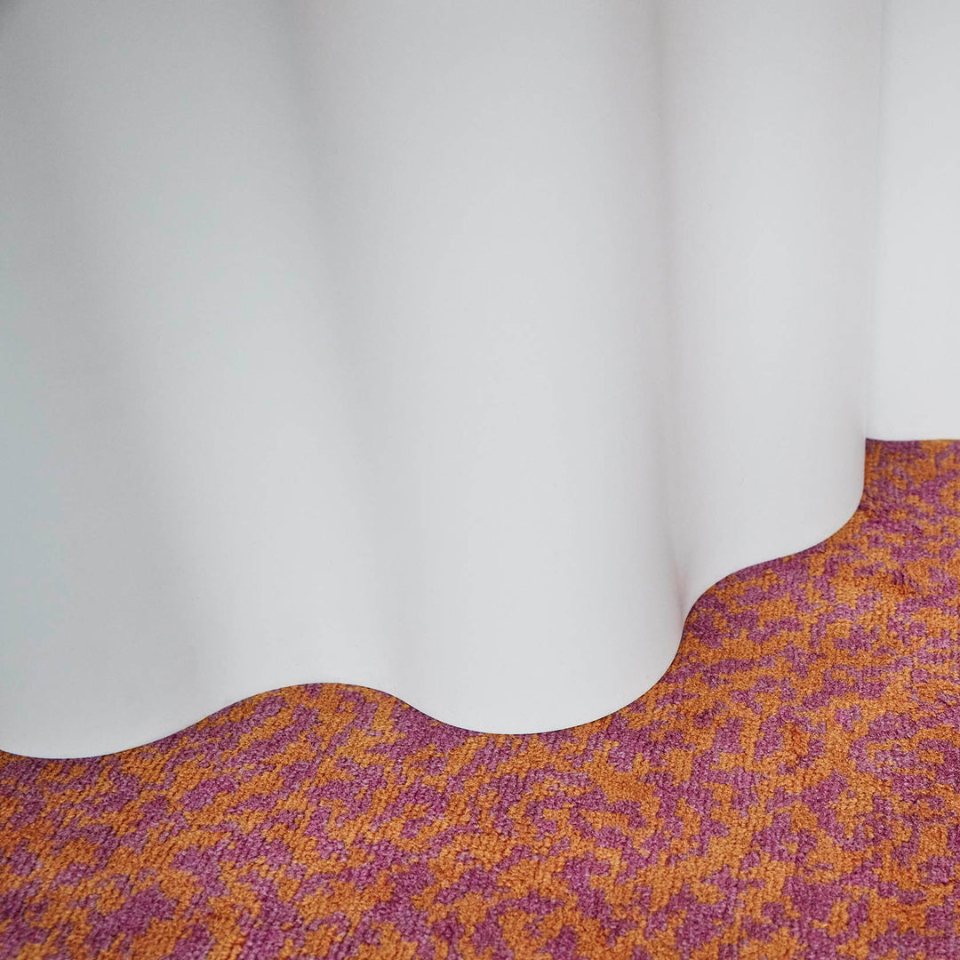 "Textured orange and purple patterned carpet with a smooth, white drape."