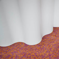 "Textured orange and purple patterned carpet with a smooth, white drape."