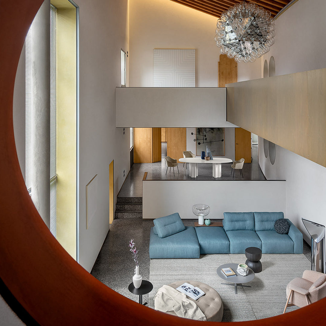 Elegant interior featuring a soft blue sectional sofa, neutral walls, and modern decor accents in light wood and metallic tones.