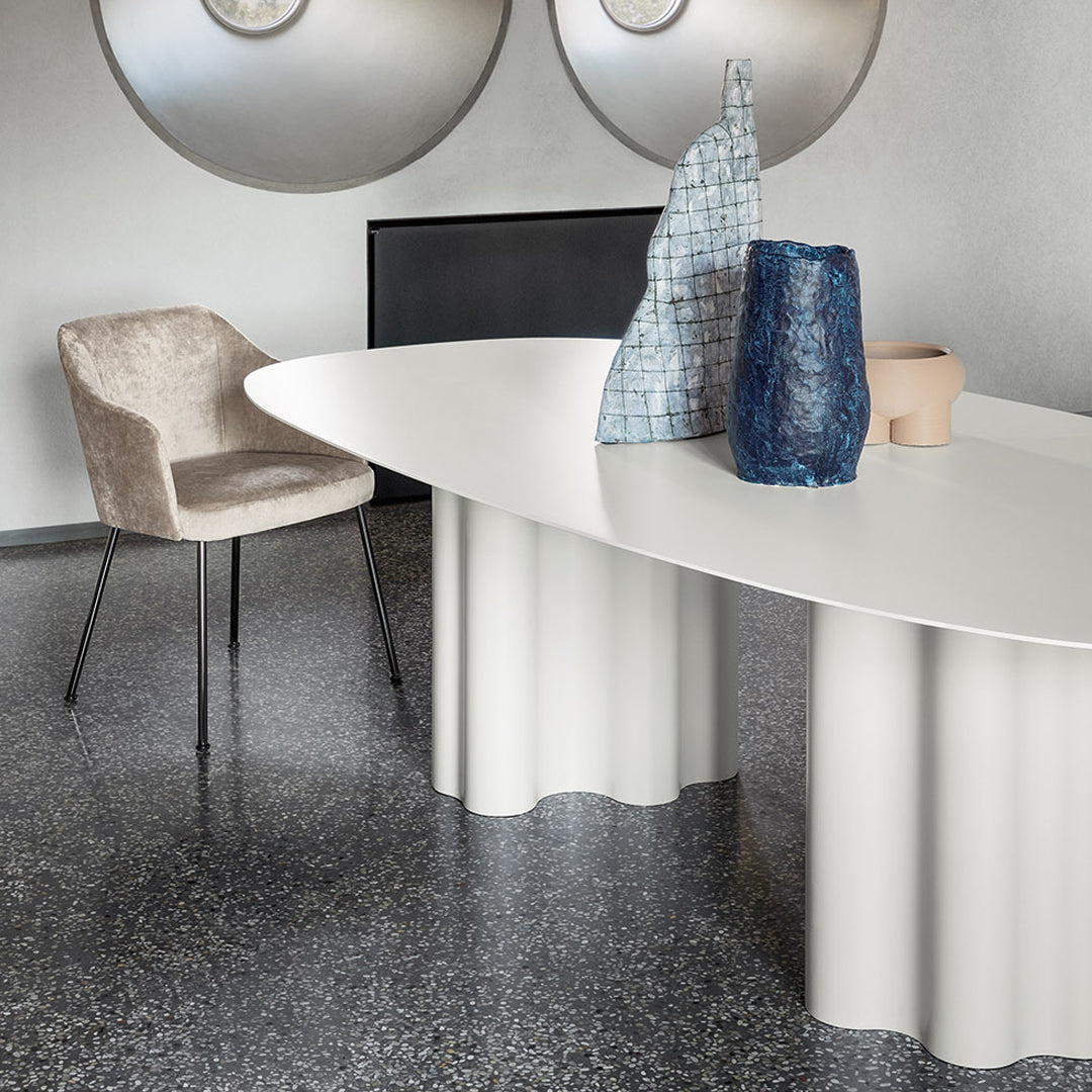 Elegant oval white table with textured taupe chair and striking blue and gray vases, set against a modern backdrop.