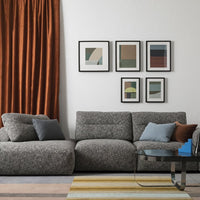 Gray textured sofa with blue and orange cushions, paired with an orange curtain and a striped yellow, blue, and gray rug.