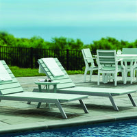 Light green pool loungers and white outdoor furniture against a serene blue pool and lush green landscape.