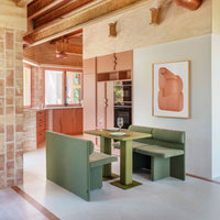 Modern dining area featuring muted green furniture, soft pink cabinets, and light wooden accents in a vibrant, open layout.