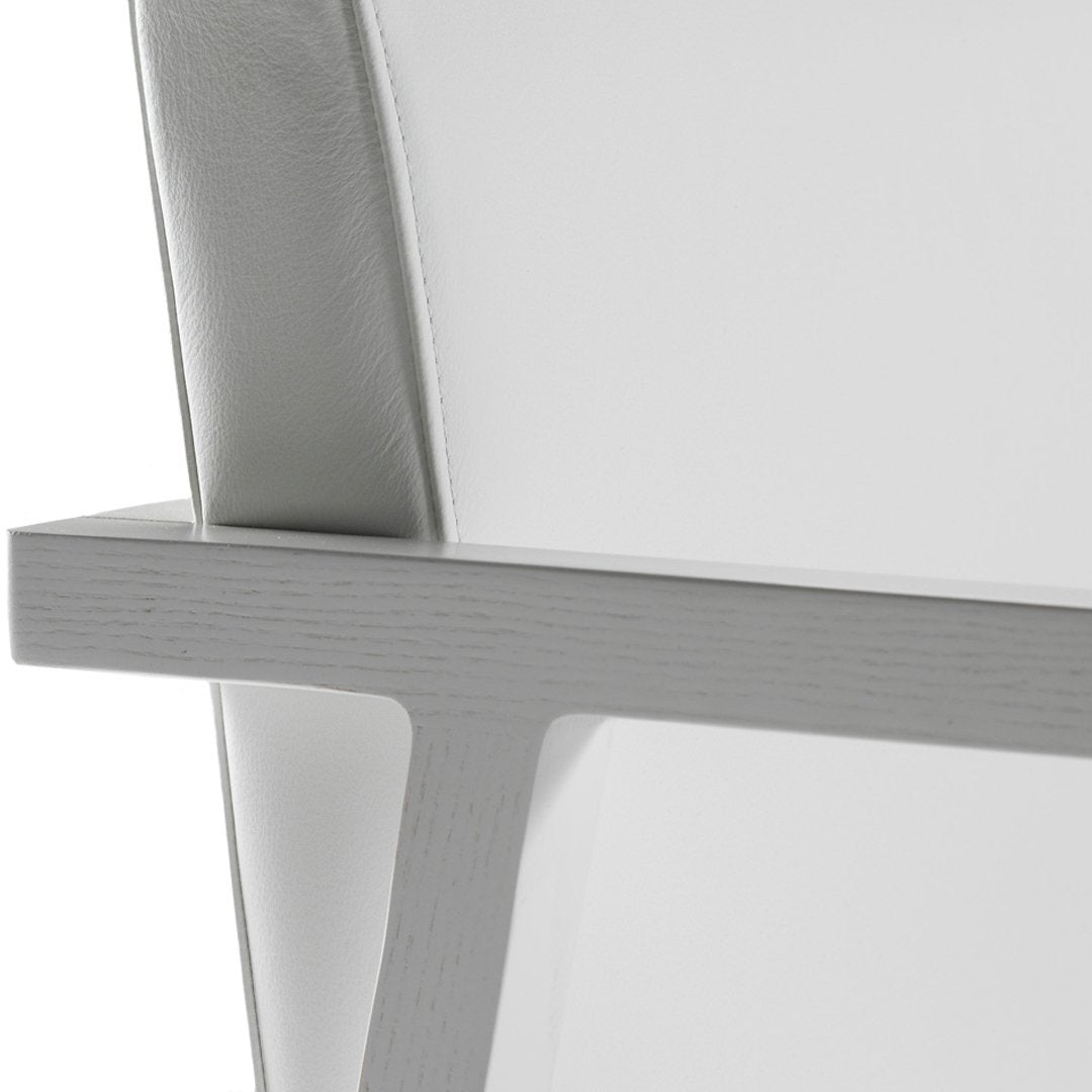 "White minimalist chair with a sleek gray wooden frame and soft curved backrest."