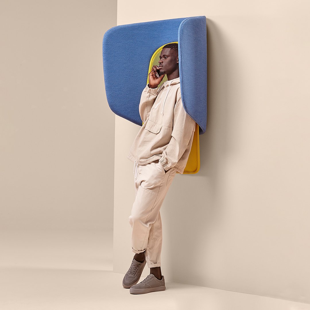 Beige hoodie and joggers with blue and yellow wall-mounted seating, creating a modern, minimalist aesthetic.