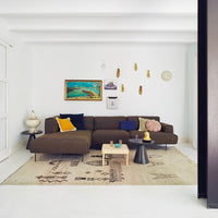 Brown sectional sofa with vibrant yellow, blue, and pink pillows; intricate patterned area rug in neutral tones.