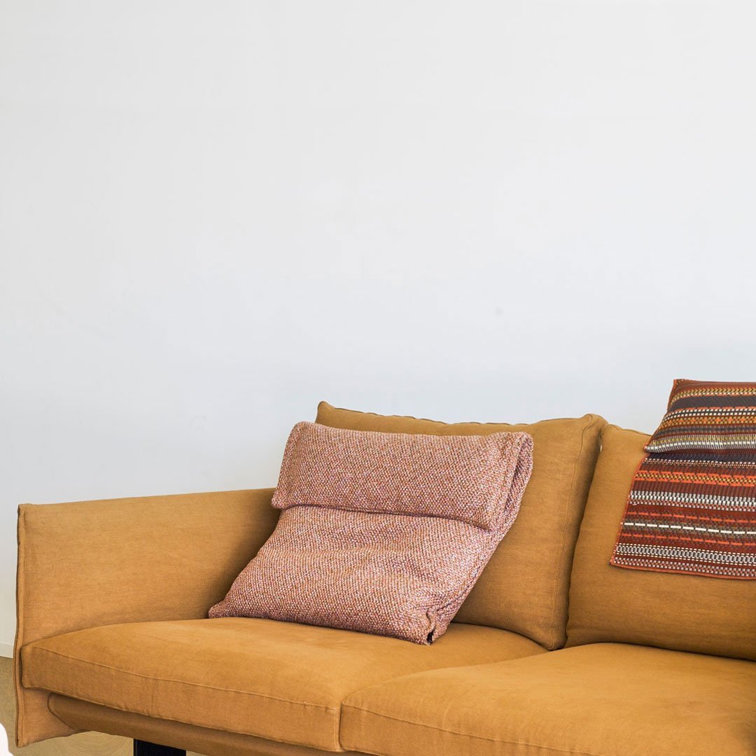Mustard yellow sofa with textured pink and patterned striped cushions. Simple and modern design.
