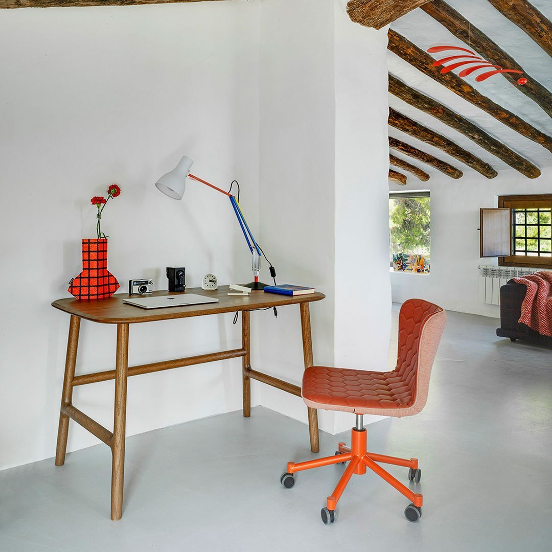 Orange and red checkered vase and chair against a minimalist white backdrop with wooden beams.