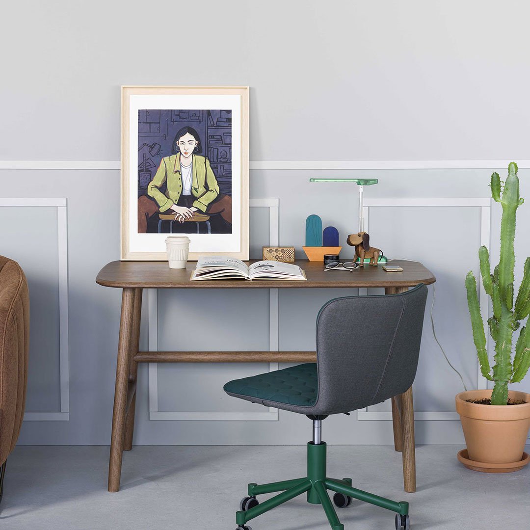 Stylish gray desk with green chair, featuring a colorful artwork and a modern green lamp, set against a neutral backdrop.