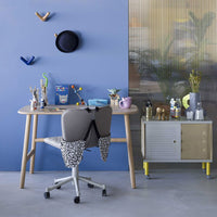 "Light blue wall with colorful decor, gray ergonomic chair with patterned back, and stylish neutral furniture."
