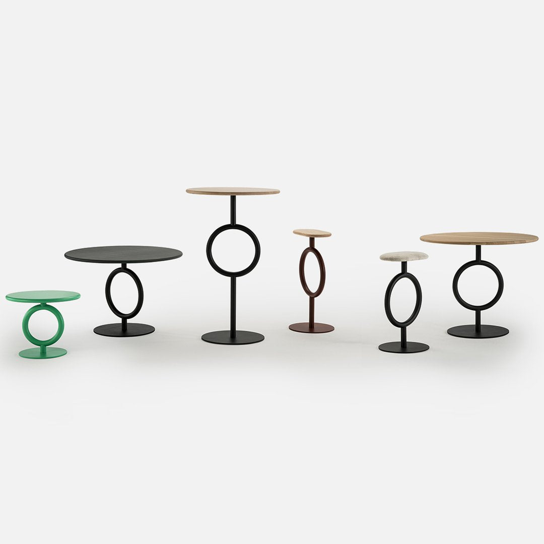 Modern side tables in black, green, brown, and natural wood with circular bases and tops, showcasing minimalist design.